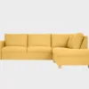 Nemo avokulmasohva keltaisella kankaalla verhoiltuna ja jalkana alaspäin kapeneva kantikas tammijalka. Tuotekuva edestäpäin, jossa divaani oikealla puolella.