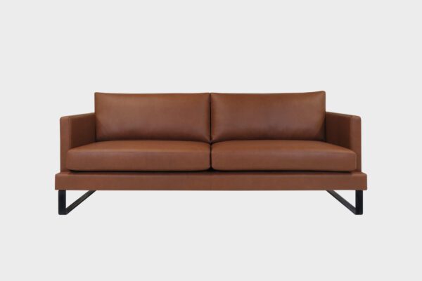 Helsinki-kolmen istuttava sohva verhoiltuna ruskealla Antique brown nahkalla ja jalkana metallinen kelkkajalka, tuotekuva edestäpäin kuvattuna.