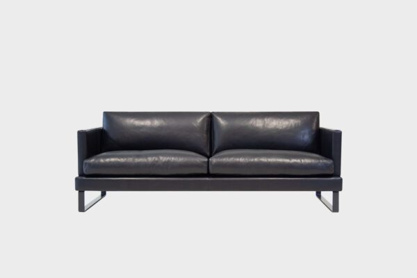 Helsinki-3 istuttava sohva mustalla nahkalla verhoiltuna ja jalkana musta kelkkajalka, tuotekuva edestäpäin kuvattuna.