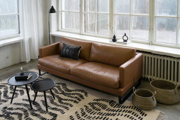 Helsinki-sohva ruskealla nahkaverhoilulla, mustanvärisillä metallisilla kelkkajaloilla, sisustuskuva.