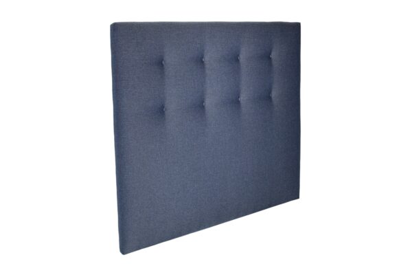 Kotimainen napeilla koristeltu sängynpääty verhoiltuna sinisellä kankaalla, tuotekuva viistosti kuvattuna.