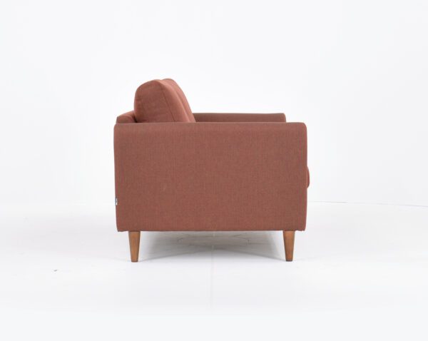 Kuura-2,5 istuttava sohva punertavalla kankaalla verhoiltuna ja jalkana pähkinä puujalka, tuotekuva sivusta kuvattuna.