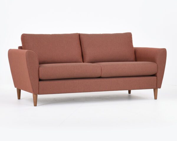 Kuura-2,5 istuttava sohva punertavalla kankaalla verhoiltuna ja jalkana pähkinä puujalka, tuotekuva viistosti kuvattuna.