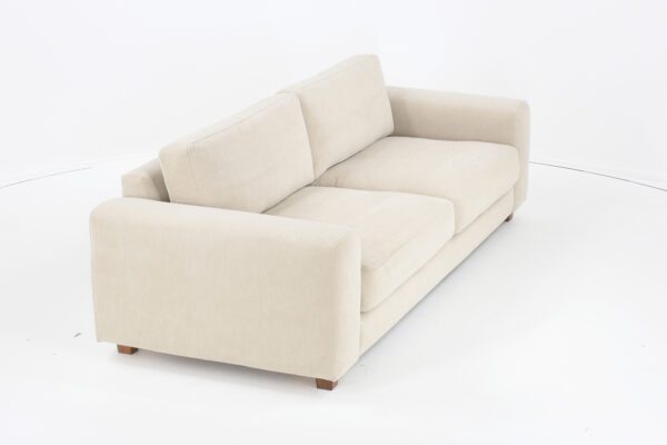 Lumo-3 istuttava sohva vaalealla kankaalla verhoiltuna ja jalkana pähkinä puujalka, tuotekuva viistosti kuvattuna.