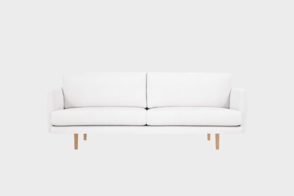 Kataja-kolmen istuttava sohva valkoisella villabukleekankaalla verhoiltuna ja tammen sävyisillä puujaloilla, tuotekuva.