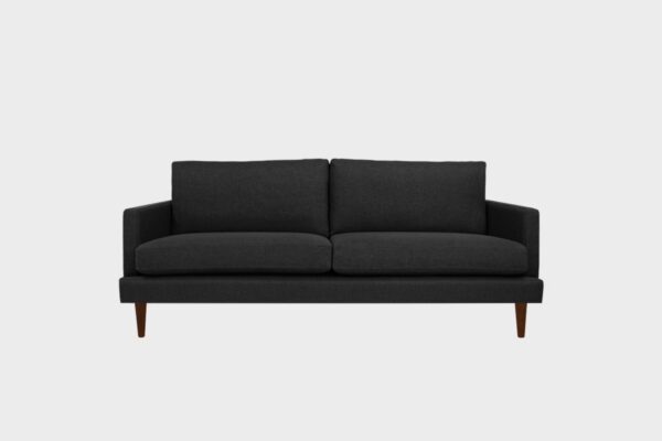 Koli-kolmen istuttava sohva verhoiltuna mustan sävyisellä kankaalla ja pähkinän värisillä jaloilla, tuotekuva.