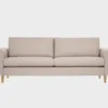Kuura-3 istuttava sohva beigellä kankaalla verhoiltuna ja jalkana tammen sävyiset puujalat, tuotekuva.