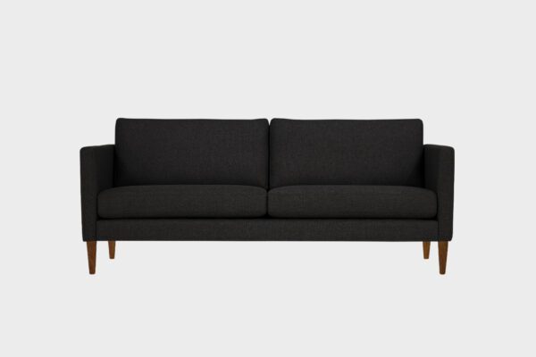 Tuohi-kolmen istuttava sohva verhoiltuna mustalla kankaalla ja pähkinän värisillä puujaloilla, tuotekuva kuvattuna edestä.
