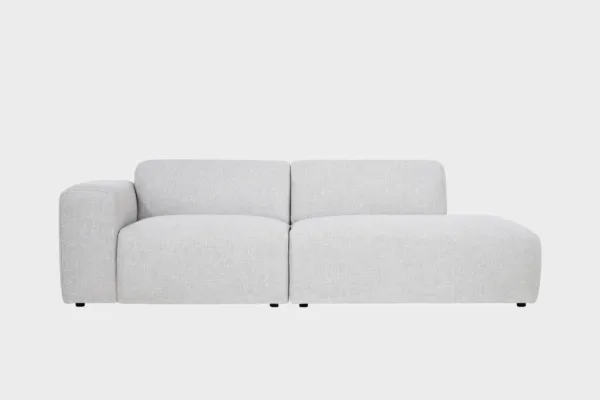 Boho-avodivaanisohva vaaleanharmaalla kankaalla verhoiltuna, käsinoja vasemmalla ja divaaniosuus oikealla vaaleaa taustaa vasten.