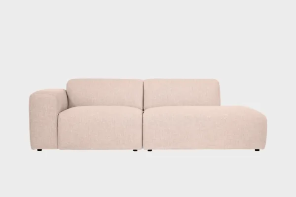 Boho-avodivaanisohva vaaleanpunertavalla kankaalla verhoiltuna, käsinoja vasemmalla ja divaaniosuus oikealla vaaleaa taustaa vasten.