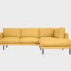 Havu pieni avokulmasohva keltaisella Stark-kankaalla verhoiltuna. Divaani oikealla puolella ja 18 cm korkeat mustat metallijalat. Tuotekuva, edestäpäin kuvattuna.