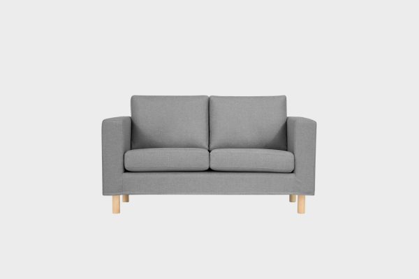 Harmaa kahden istuttava sohva koivun värisillä jaloilla kuvattuna suoraan edestäpäin.