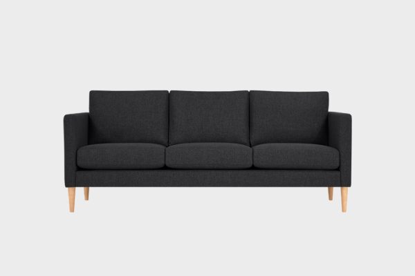 Mustalla kankaalla verhoiltu 3 istuttava sohva 3lla tyynyllä, jossa tammenväriset puujalat.