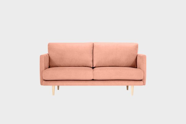 Vaaleanpunainen kahden ja puolen hengen istuttava sohva, jossa koivunväriset puujalat.