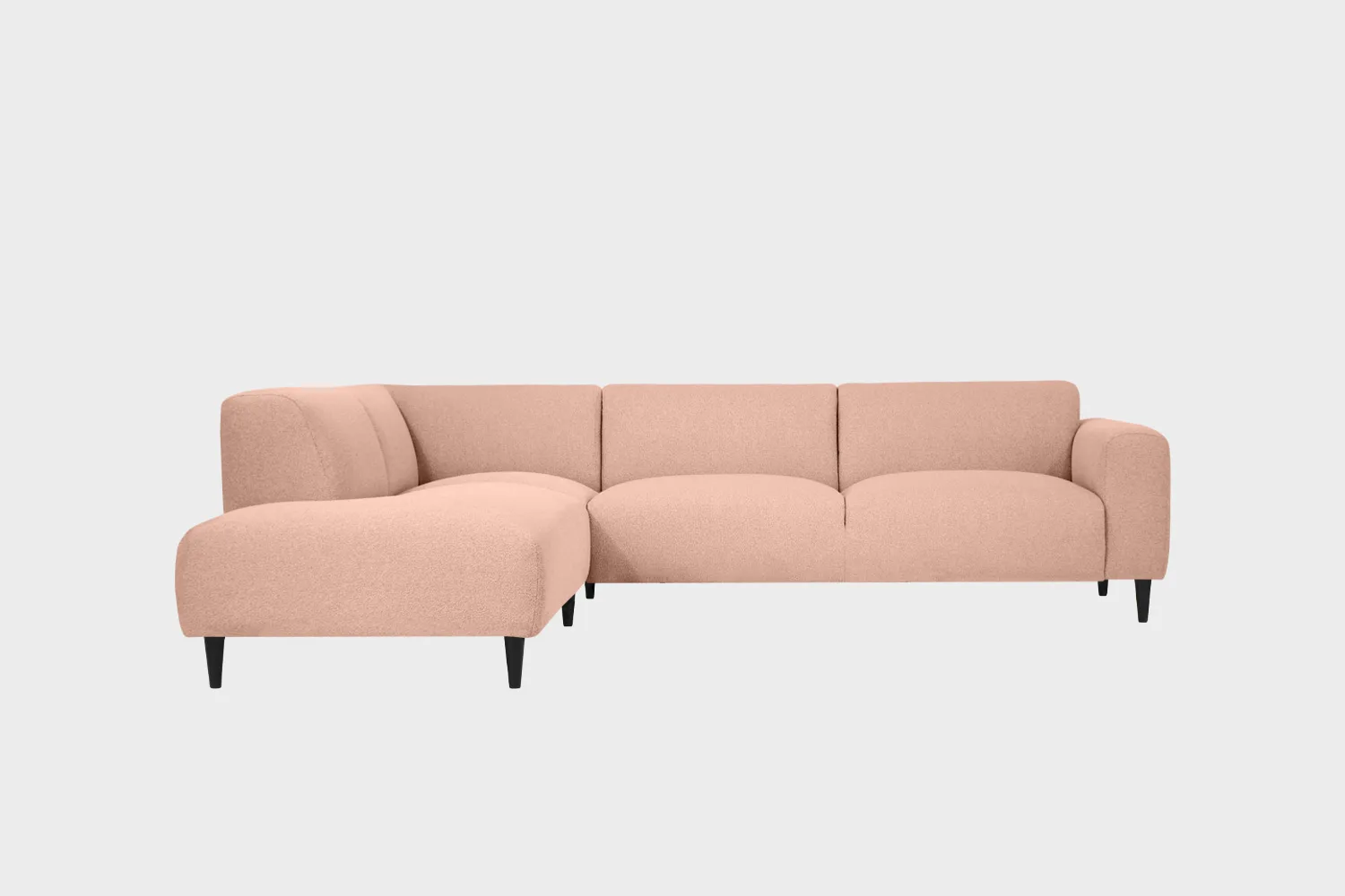 Vaaleanpunainen avokulmasohva mustilla puujaloilla ja divaanin puoli sohvan vasemmalla puolella edestä päin katsottuna.