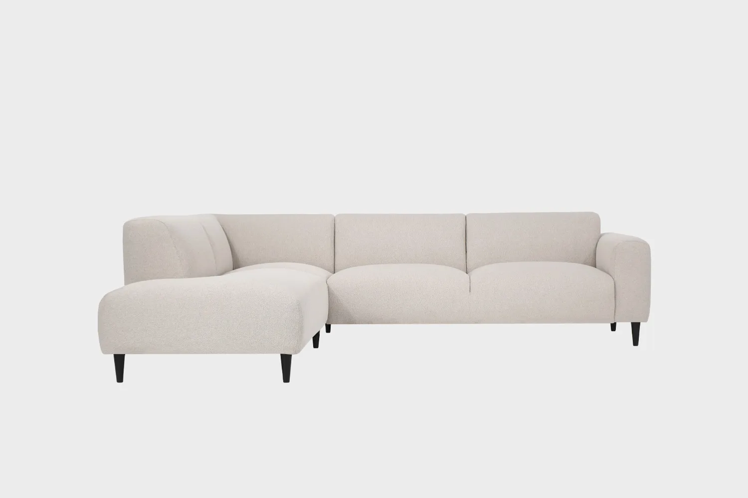 Beige avokulmasohva mustilla puujaloilla ja divaanin puoli sohvan vasemmalla puolella edestä päin katsottuna.