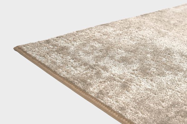 Beige VM Carpet Basaltti matto. Lähikuva maton kulmasta, josta näkyy kanttaus ja maton materiaali.