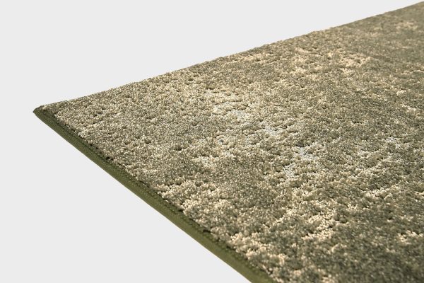 Vihreä VM Carpet Basaltti matto. Lähikuva maton kulmasta, josta näkyy kanttaus ja maton materiaali.