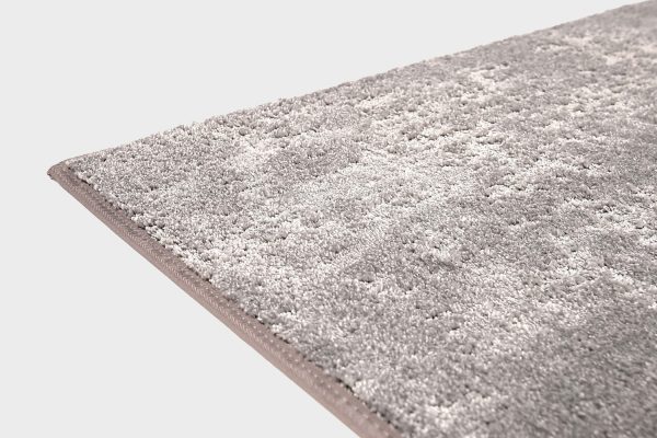 Harmaa VM Carpet Basaltti matto. Lähikuva maton kulmasta, josta näkyy kanttaus ja maton materiaali.