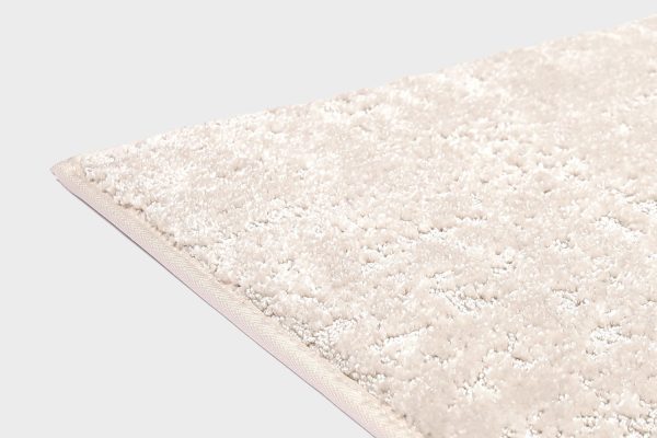 Valkoinen VM Carpet Basaltti matto. Lähikuva maton kulmasta, josta näkyy kanttaus ja maton materiaali.