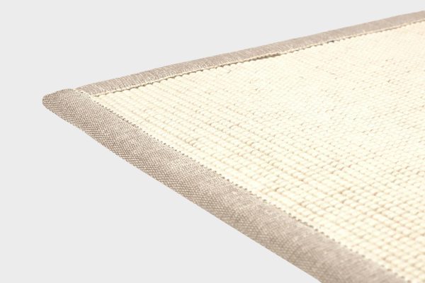 Valkoinen VM Carpet Esmeralda matto. Lähikuva maton kulmasta, josta näkyy kanttaus ja maton materiaali.