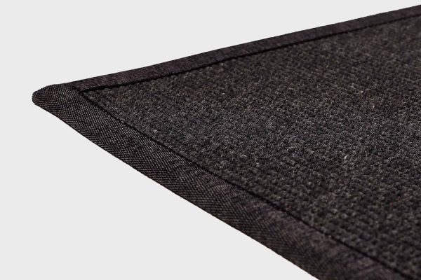 Musta VM Carpet Esmeralda matto. Lähikuva maton kulmasta, josta näkyy kanttaus ja maton materiaali.