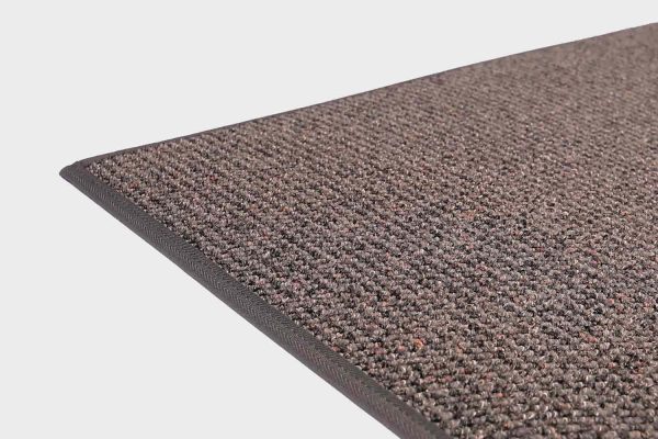 Tummanharmaa VM Carpet Tweed matto. Lähikuva maton kulmasta, josta näkyy kanttaus ja maton materiaali.