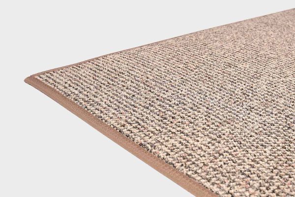 Vaalean beige VM Carpet Tweed matto. Lähikuva maton kulmasta, josta näkyy kanttaus ja maton materiaali.