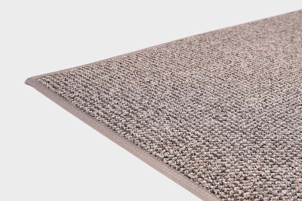 Harmaa VM Carpet Tweed matto. Lähikuva maton kulmasta, josta näkyy kanttaus ja maton materiaali.