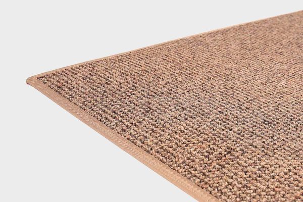 Vaaleanruskea VM Carpet Tweed matto. Lähikuva maton kulmasta, josta näkyy kanttaus ja maton materiaali.