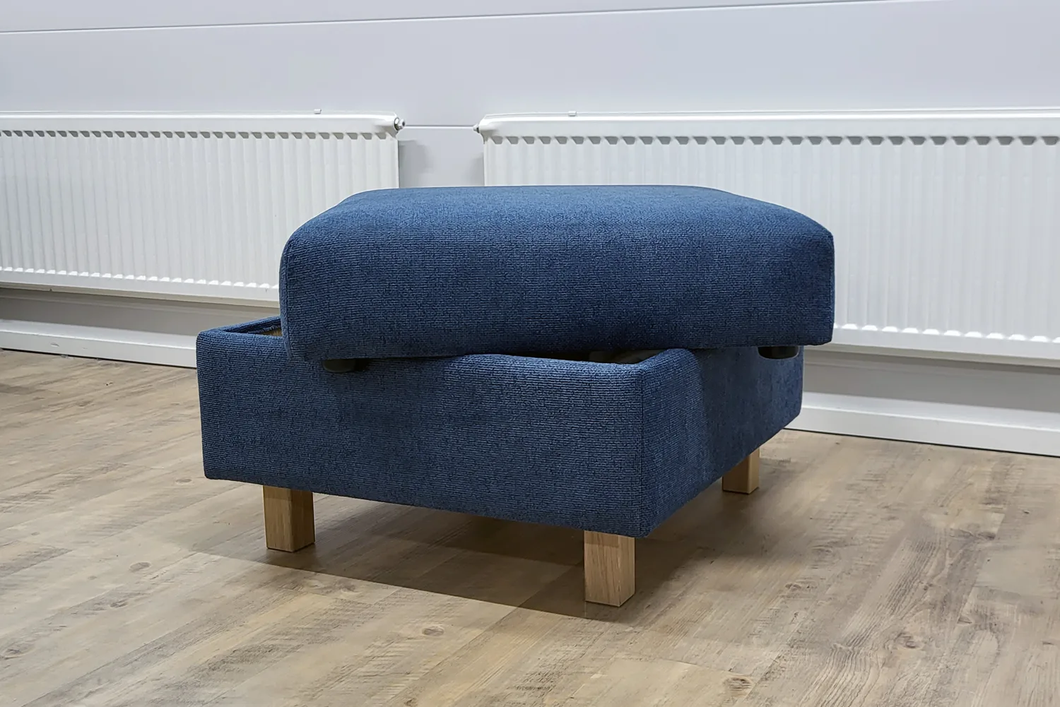 Sininen rahi tammen värisillä jaloilla kuvattuna viistosti edestä. Säilytysrahin kansi on avattuna.