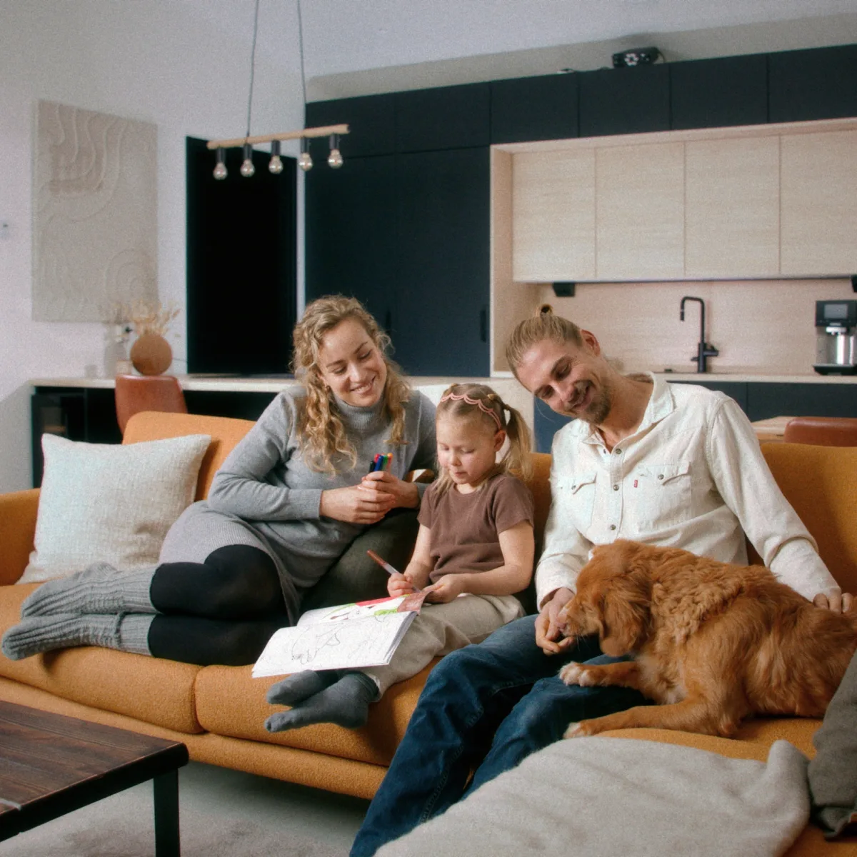 Perhe oranssilla sohvalla modernissa olohuoneessa.