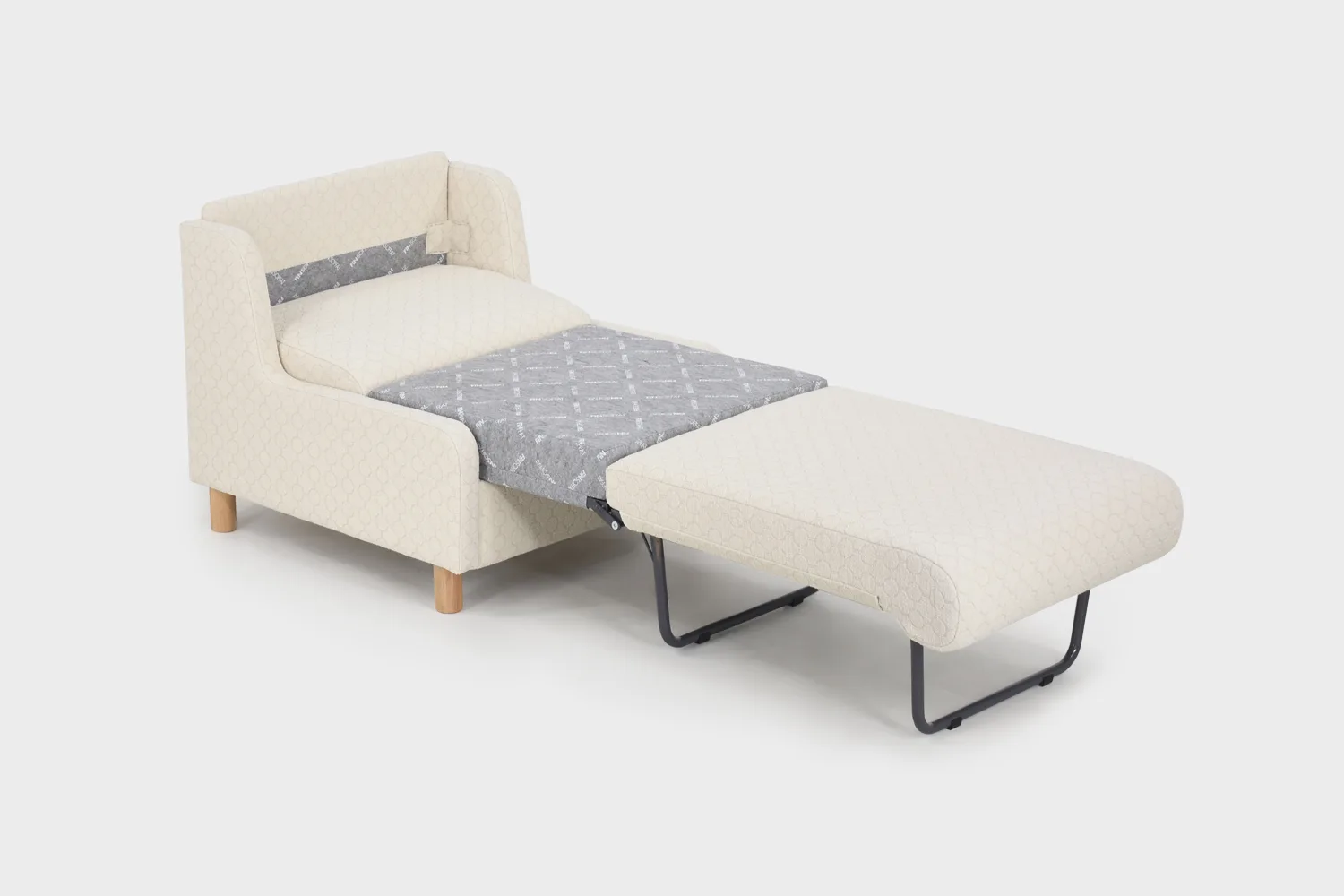 Luonnonvalkoinen vuodetuoli tammisin jaloin kuvattuna viistosti vaaleaa taustaa vasten vuode avattuna.