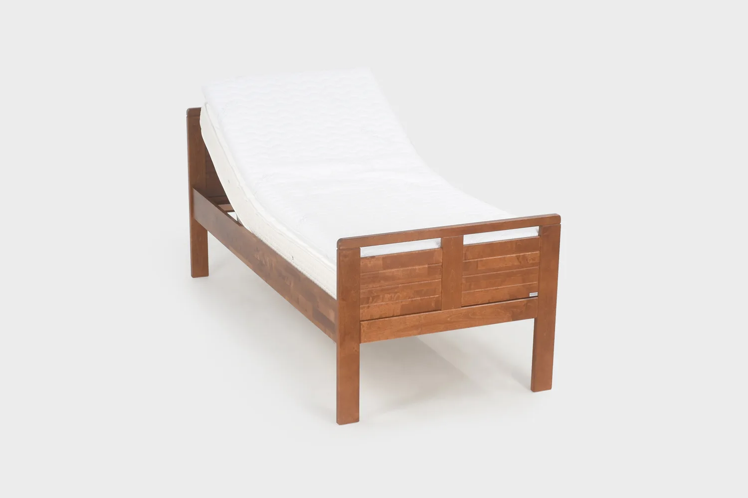 Korkea moottoroitu seniorisänky 80x200 cm pähkinänvärisenä kuvattuna viistosti edestäpäin pääty hieman kohotettuna.