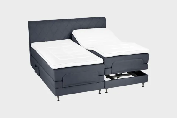 Tummanharmaa moottorisänky 200x200 cm mustilla jaloilla sekä samanvärisellä sängynpäädyllä. Parisänky on kuvattuna viistosti toisen sänkypuoliskon päädyt aavistuksen koholla vaaleaa taustaa vasten.
