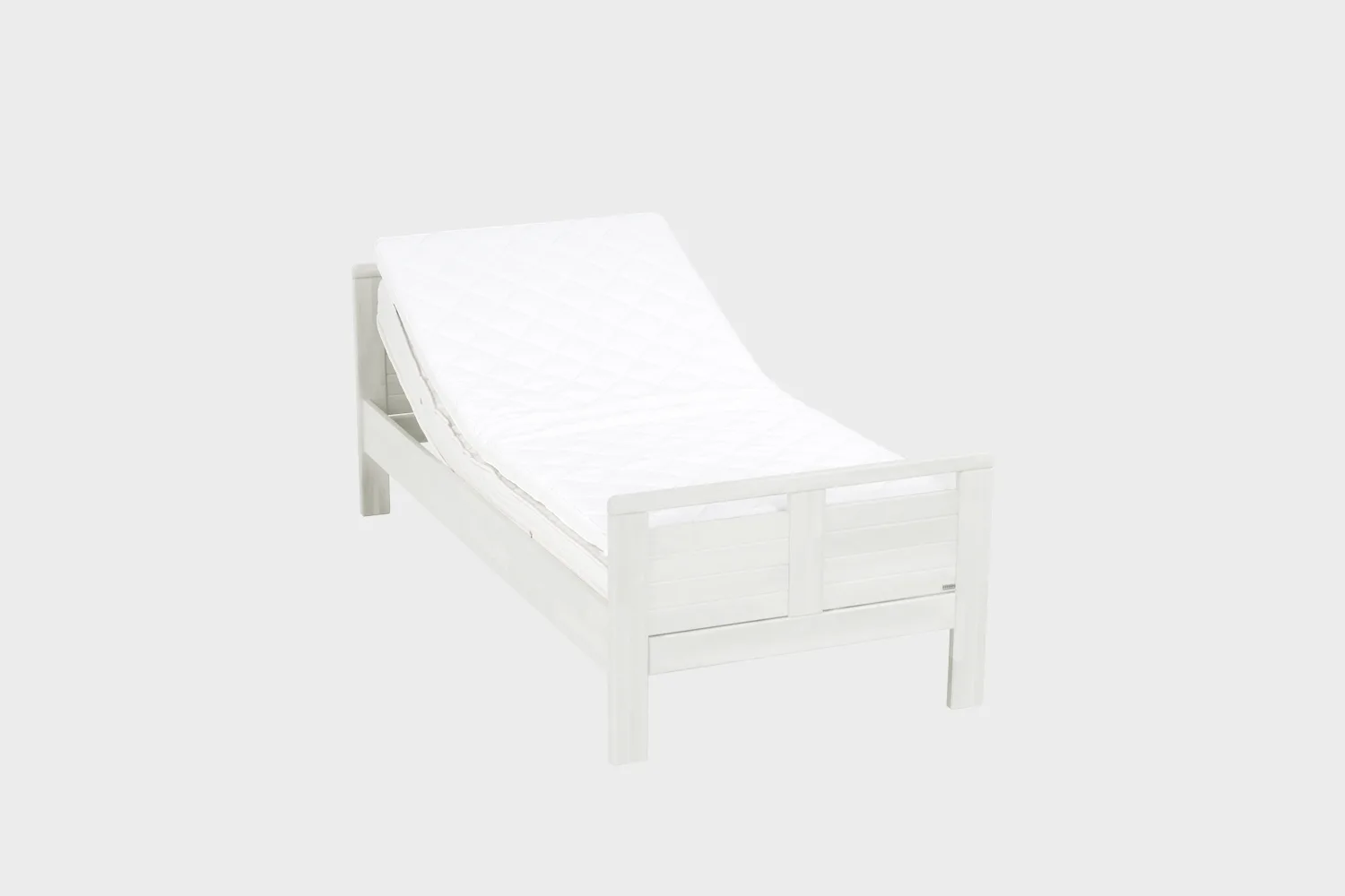 Matala moottoroitu seniorisänky 80x200 cm valkoisena kuvattuna viistosti edestäpäin pääty hieman kohotettuna.