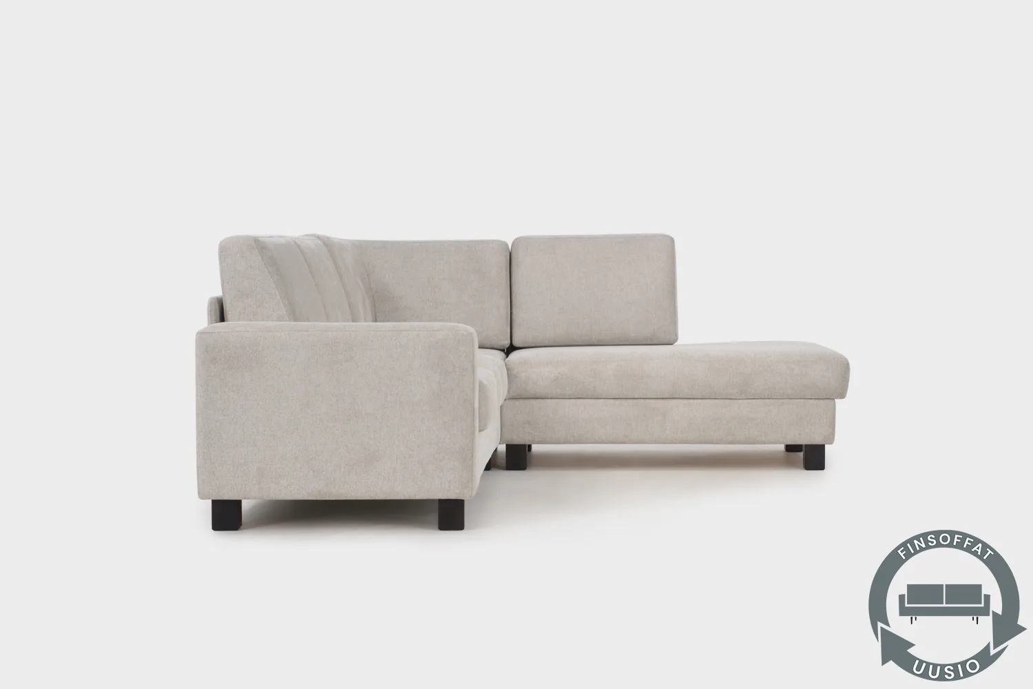 Vaalean beige vuodesohva AINA divaaniosalla kuvattuna sivustapäin. Sohva on kuvattu vaalean harmaata taustaa vasten.