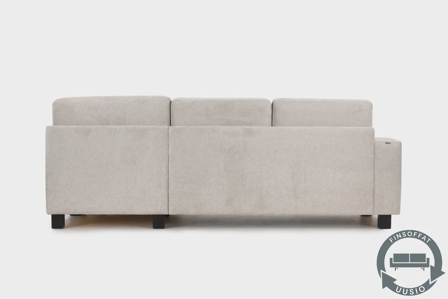 Vaalean beige vuodesohva AINA divaaniosalla kuvattuna suoraan takaapäin. Sohva on kuvattu vaalean harmaata taustaa vasten.